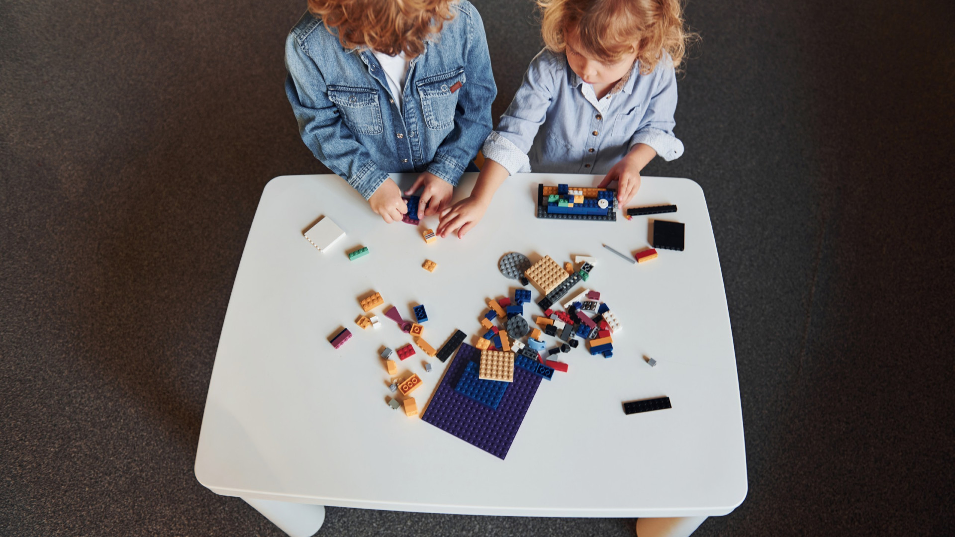 Little friends have fun with construction toys in playroom. Kindergarten educational games.